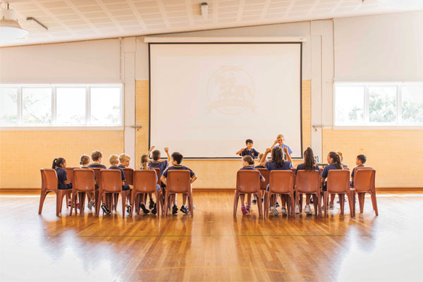 Students presenting to a group of students in the school hall