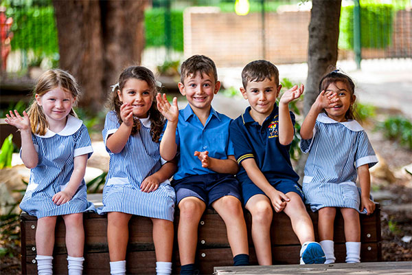 Students at St Joan of Arc Catholic Primary School smiling and waving